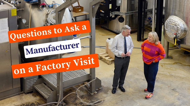 Kate in an orange jumper asking questions to a manufacturer wearing a shirt and tie. They are in a textile factory dyehouse in Derbyshire.
The words Questions to Ask a Manufacturer on a Factory Visit are on the image.